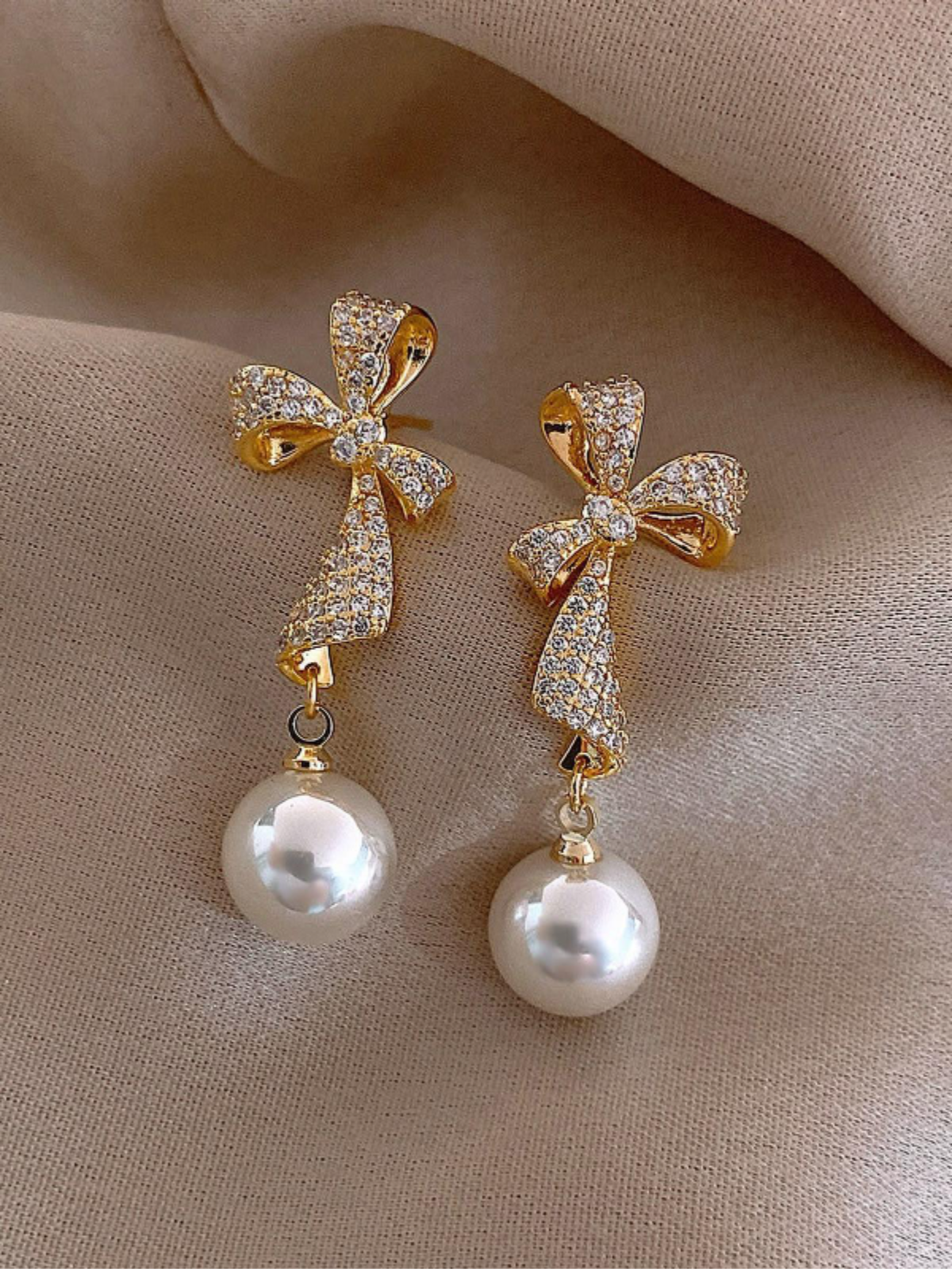 elegant crystal-studded bow and pearl drop earrings